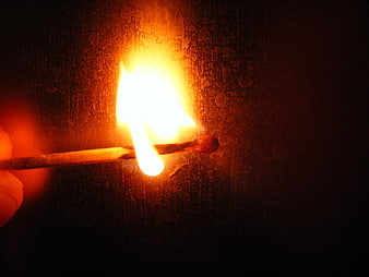 Lit Matchstick Burning Against Dark Textured Background