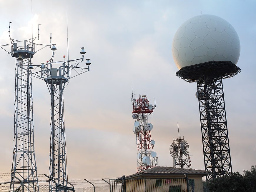 Radar dome and communication towers against cloudy sky