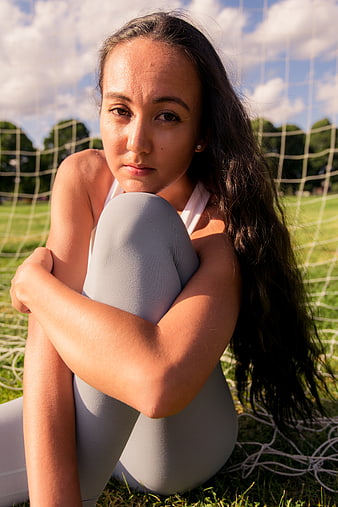 Young female athlete resting on grass field near soccer net