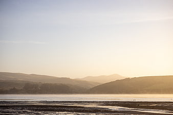 Serene Sunrise Over Misty Marshland and Rolling Hills
