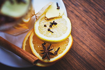 Sliced citrus fruits with cinnamon, cloves, and star anise on a wooden table