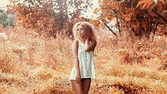 Young woman in white dress standing in autumn field