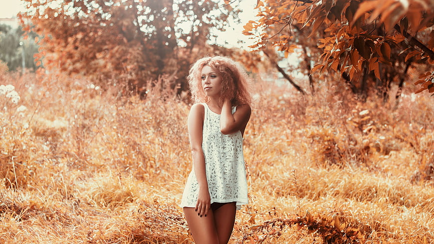 Young woman in white dress standing in autumn field