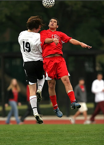 Two soccer players jumping for a header in action