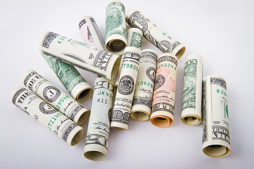 Rolled US Dollar Bills Scattered on White Background
