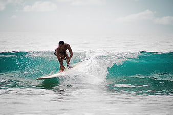 Male Surfer Riding Turquoise Wave in Ocean