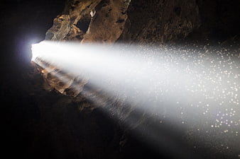 Sunbeam shining through cave opening with sparkling dust particles