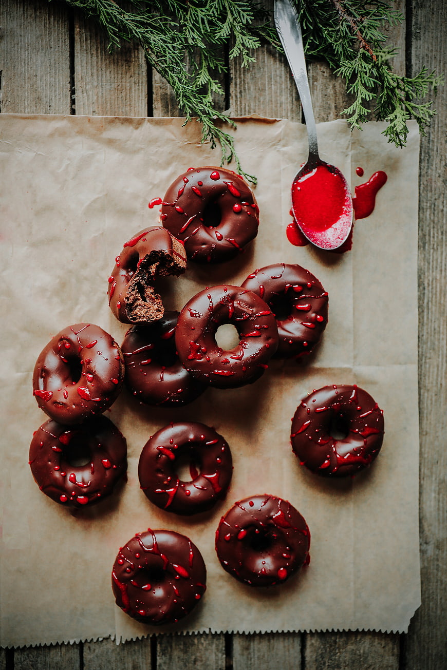 Chocolate donuts with red glaze on parchment paper
