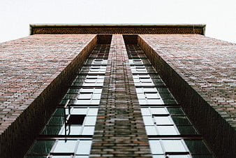 Low angle view of tall brick building facade with windows