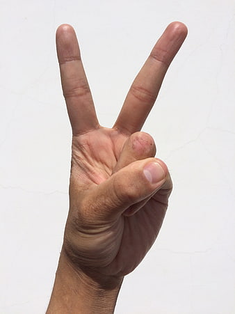 Hand making peace sign gesture against white background