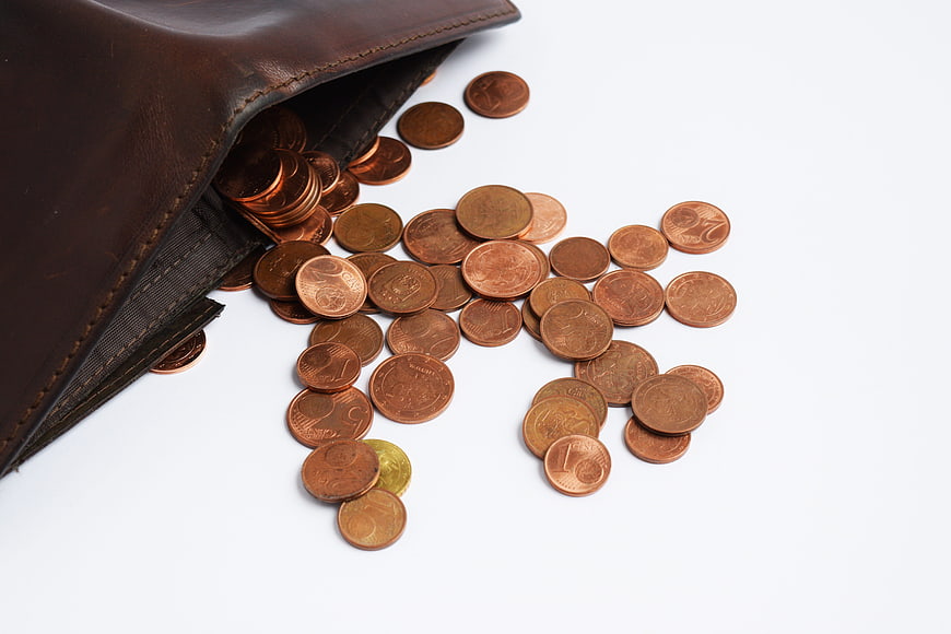 Euro coins spilling from brown leather wallet on white background