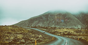 Car driving on winding road through misty mountain landscape