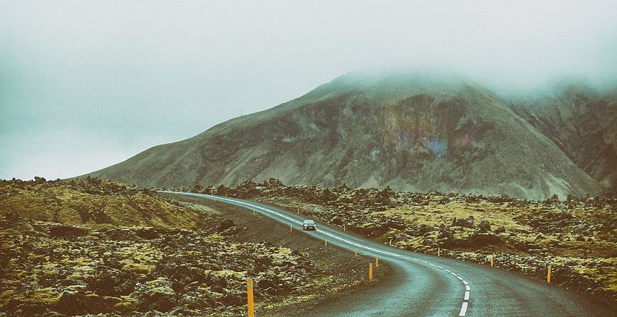 Car driving on winding road through misty mountain landscape