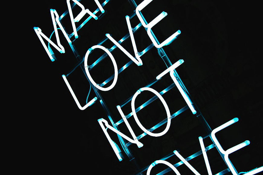 Blue Neon Sign Reading Make Love Not War on Black Background