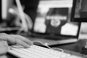 Close-up of hands typing on white keyboard with blurred laptop