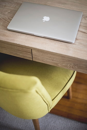Silver MacBook on wooden desk with yellow chair