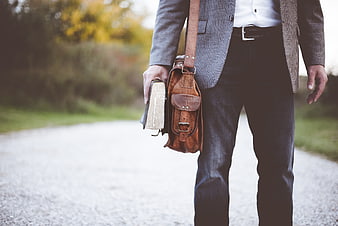 Man in Blazer Holding Leather Satchel and Book on Path