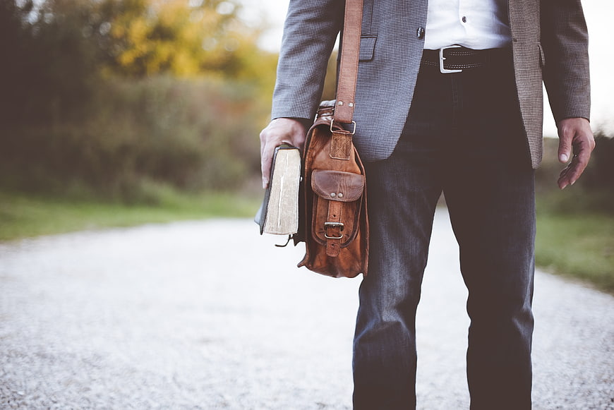 Man in Blazer Holding Leather Satchel and Book on Path