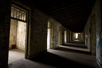 Dark abandoned hospital corridor with peeling paint and graffiti