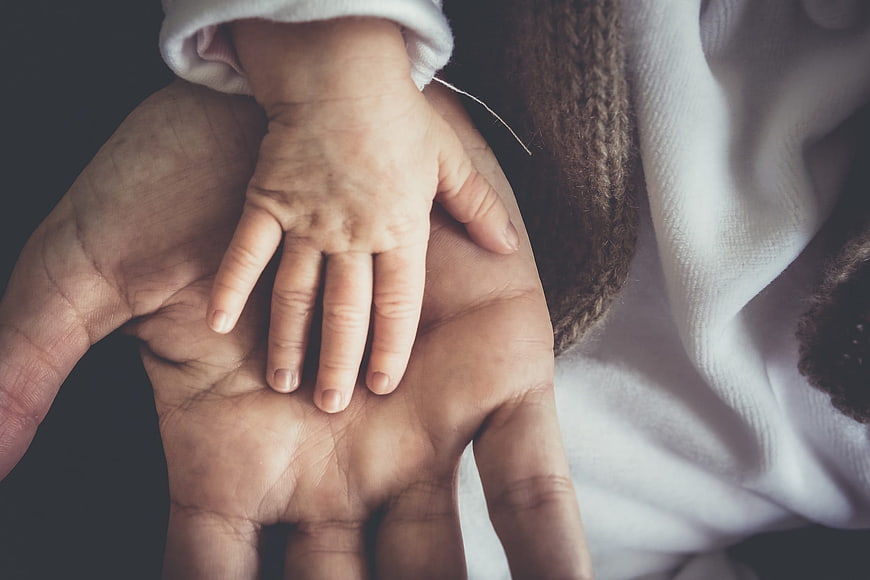Adult hand holding baby hand close up