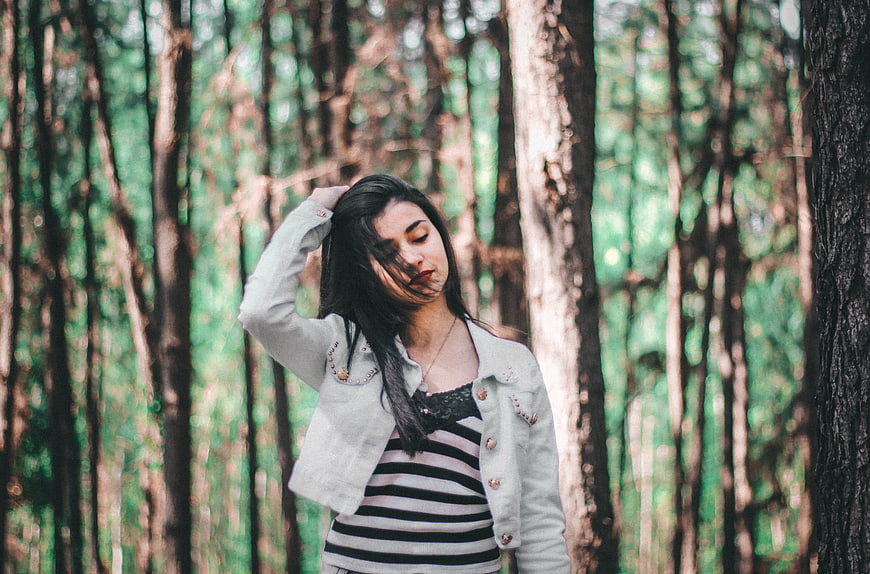 Young woman with dark hair in striped shirt and jacket in forest