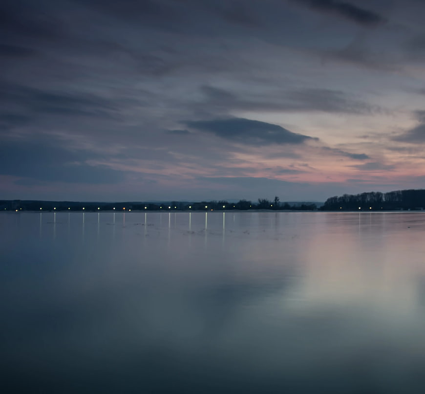 Serene Lake at Dusk with City Lights Reflection
