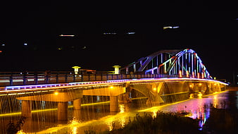 Colorful illuminated bridge with water curtain at night