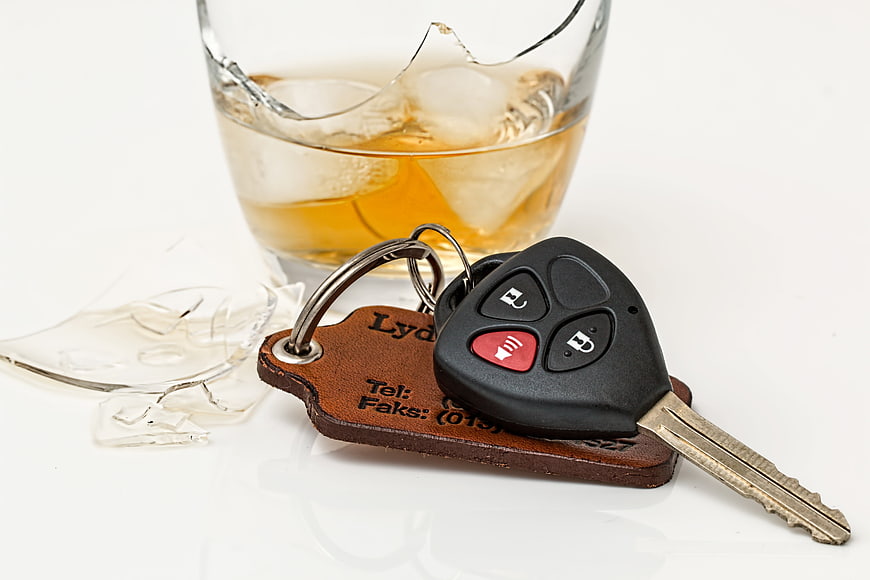 Car keys and leather tag next to a shattered glass of whiskey