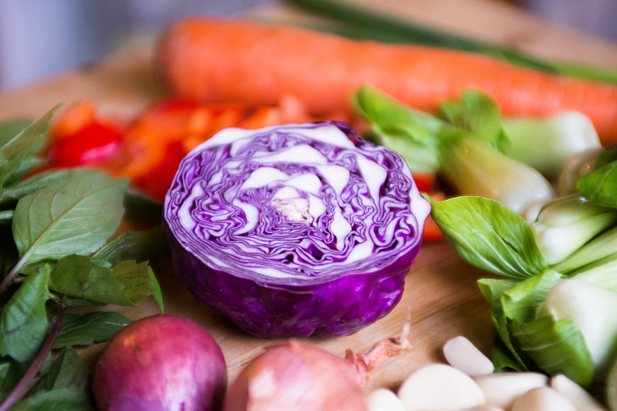 Fresh Purple Cabbage and Vegetables on Wooden Board