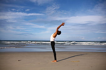 Woman performing standing yoga pose on a sandy beach