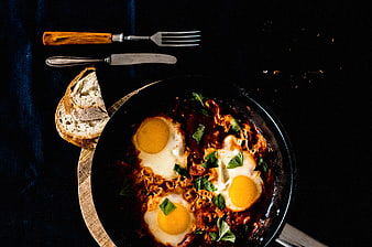 Shakshuka eggs in pan with bread and cutlery