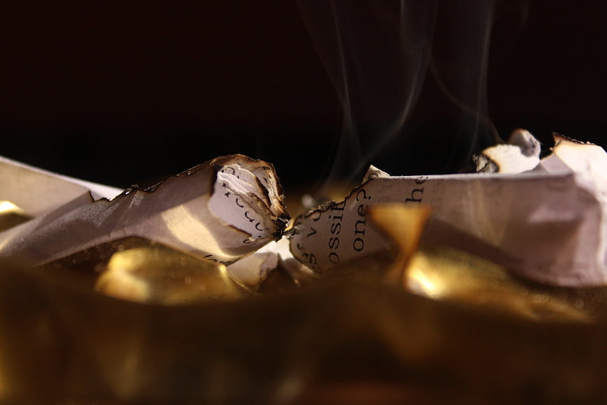 Burning paper with smoke rising in dark moody setting
