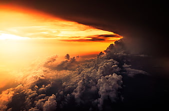 Dramatic sunset above clouds with golden light and dark storm