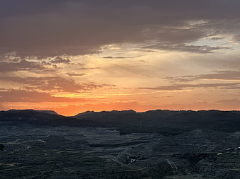 Dramatic sunset over rugged mountain landscape with orange sky