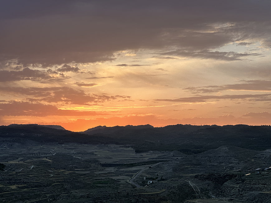 Dramatic sunset over rugged mountain landscape with orange sky
