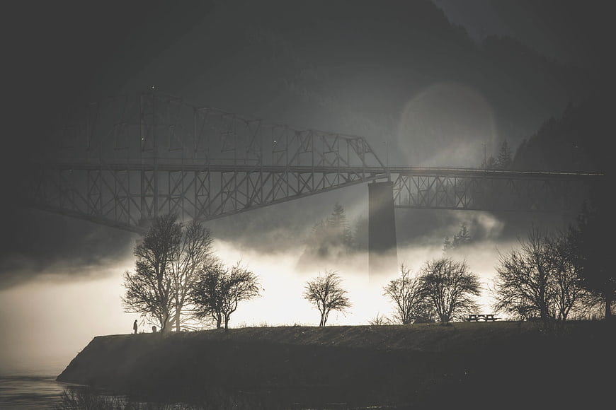 Atmospheric Grayscale Photo of Truss Bridge Over Misty River
