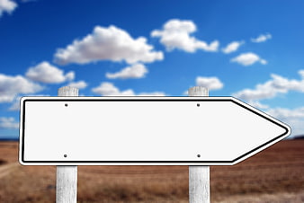 Blank White Arrow Signpost Against Blue Sky