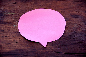 Pink speech bubble cutout on rustic wooden background