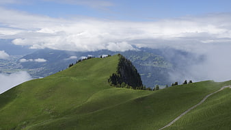 Lush green mountain ridge with clouds and valley view