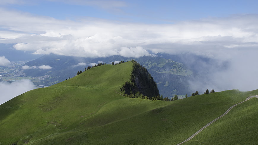 Lush green mountain ridge with clouds and valley view