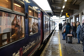 Passengers waiting on platform as blue commuter train arrives