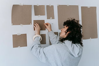 Woman arranging brown paper sheets on white wall