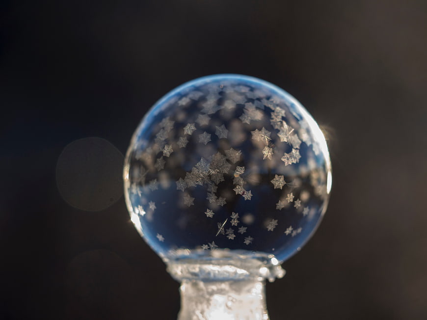 Close-up of a blue glass ornament with star-shaped snowflakes