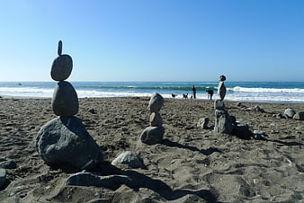 Balanced Rock Stacks on Sandy Beach with Ocean Background