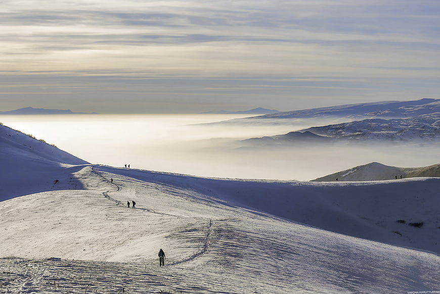 Winter Hikers on Snowy Mountain Ridge Above Clouds