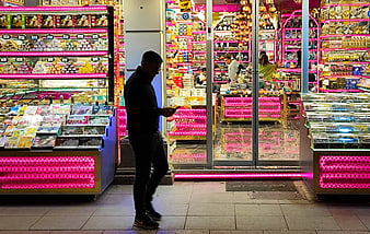Man walking past brightly lit souvenir shop at night