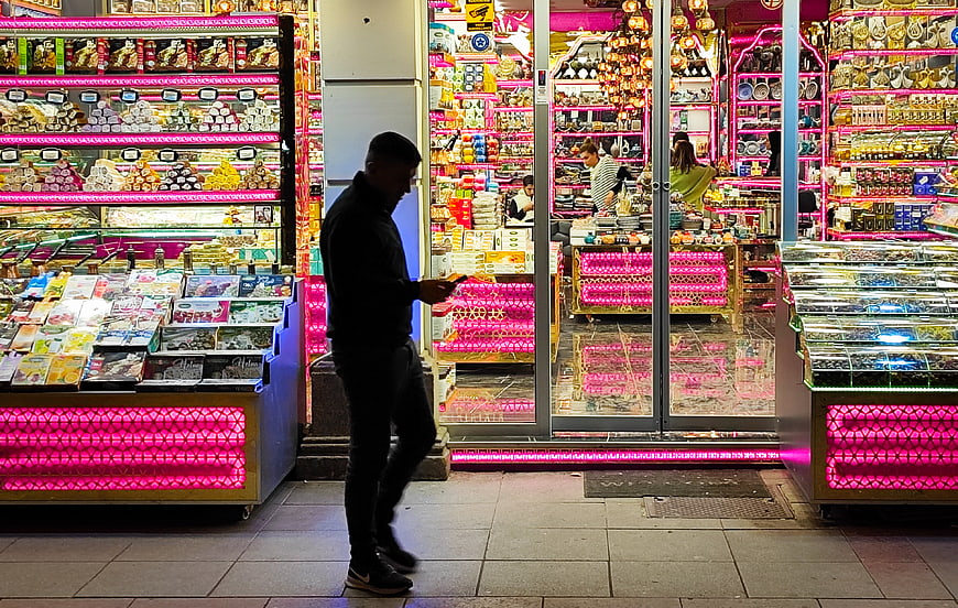Man walking past brightly lit souvenir shop at night