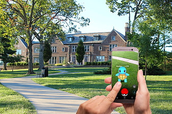 Hands holding smartphone playing Pokemon Go in park