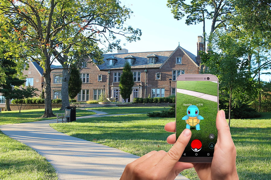 Hands holding smartphone playing Pokemon Go in park