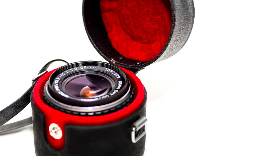Vintage Pentax Lens in Red Leather Case on White Background